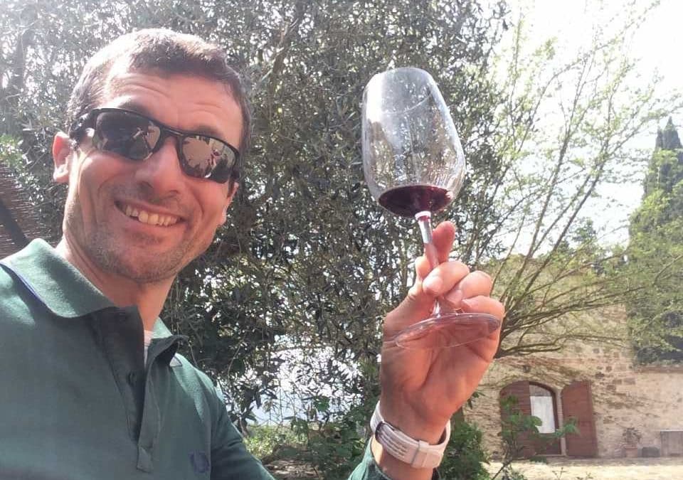 Adventure in Tuscany! Piero your tour leader in sunglasses holds up a glass of red wine, toasting to a beautiful day in Tuscany, an enjoyable moment during a "bike in Tuscany" and wine experience.