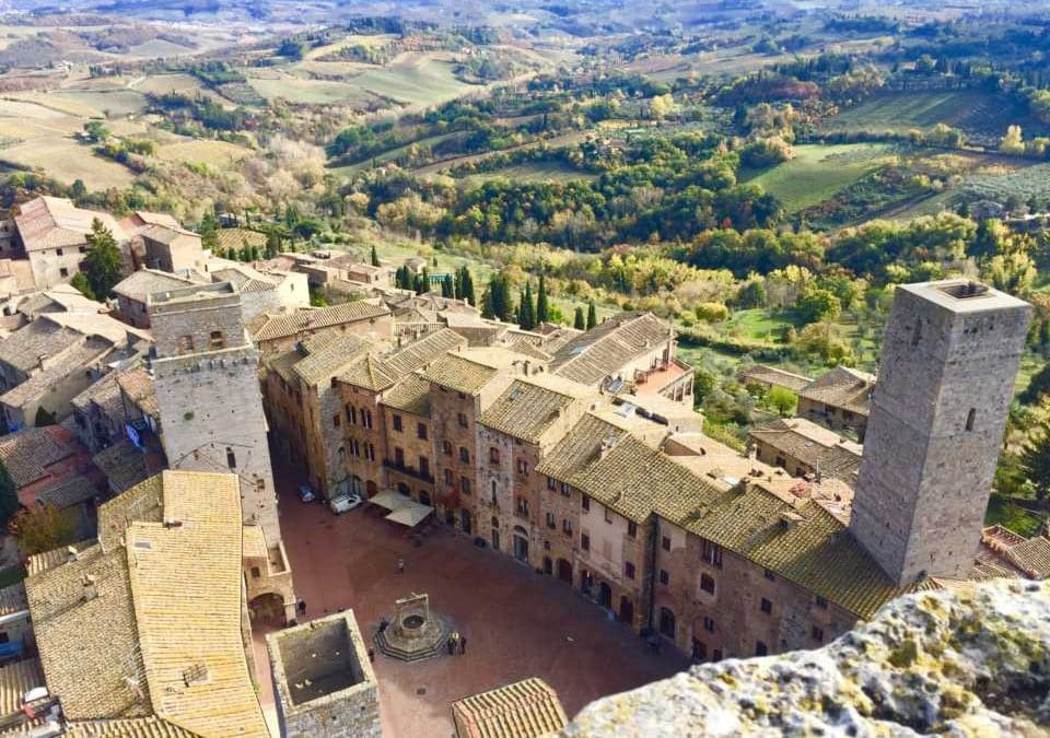 Tuscany bike tour An aerial view of San Gimignano's historic towers and rooftops, surrounded by rolling Tuscan countryside, showcasing the beautiful destination of a bike from Florence to Tuscany tour.