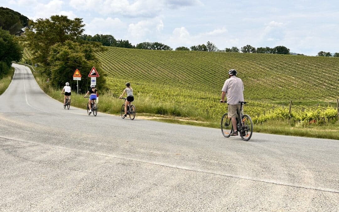 Cycling in tuscany Cyclists ride a scenic paved road winding through picturesque Tuscan vineyards using our premium electric bikes, offering an immersive experience on a private tour.