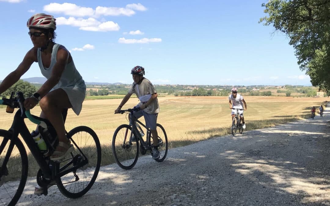 boutique bike tour Cyclists guided by Elena ride along a sunny road in the Tuscan countryside near San Gimignano, enjoying a relaxed pace on their bike in Tuscany tour